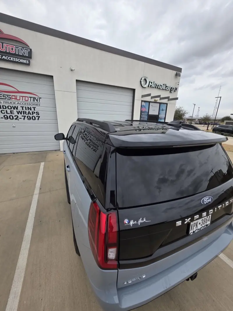 Rear of a light blue full-size SUV with tinted back glass, outside ExpressAutoTNT in Katy, TX