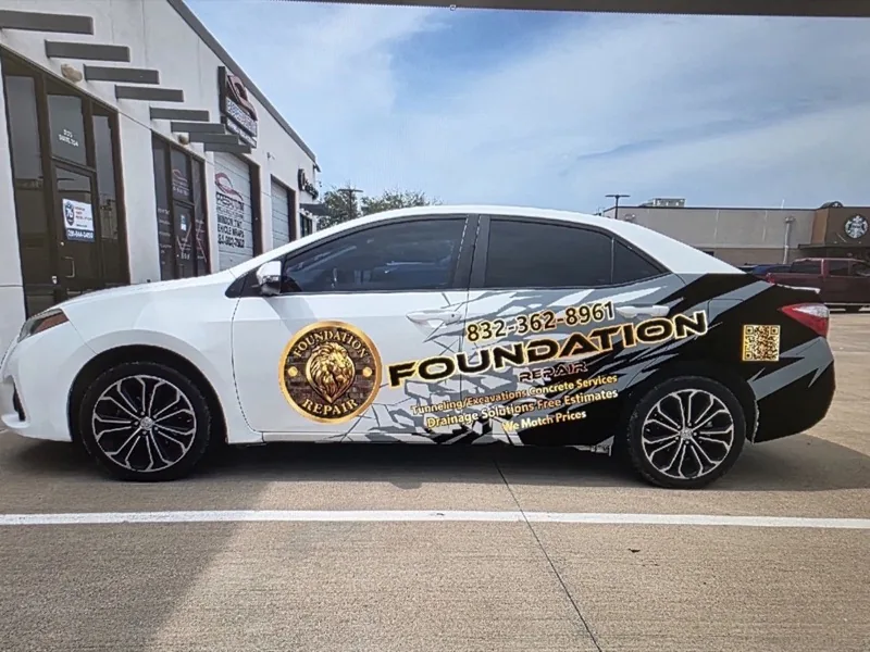 White sedan with a gold logo and lettering laid out along the doors