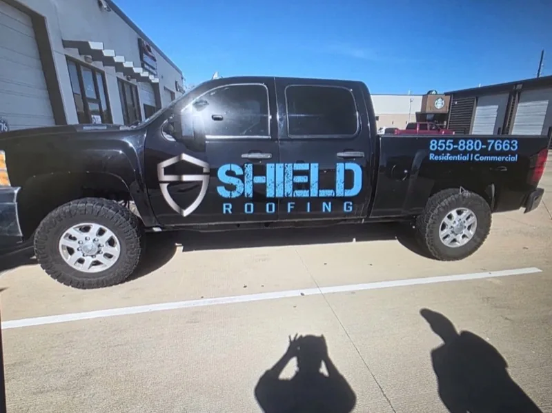 Black pickup with roofing company door graphics