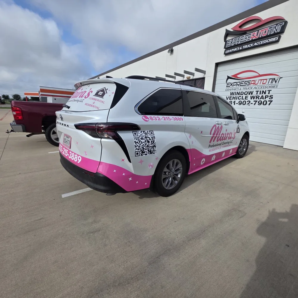 A minivan in a pink and white cleaning-company wrap, parked outside the Express Auto Tint shop